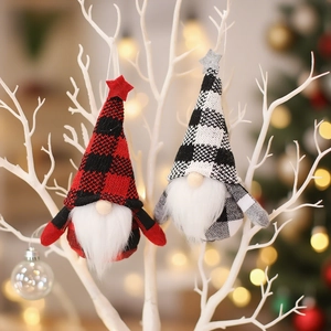 Set of two plaid Christmas gnome pendants hanging on branches with warm bokeh lights