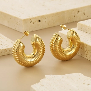 Polished gold stainless steel C-shaped hoop earrings with spiral texture on a stone base