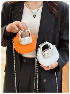 Miniature glossy chain bags in orange and white shown held by a fashion model
