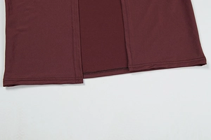 Detailed close-up of double-stitched hem on dark wine red knitted fabric for skirt