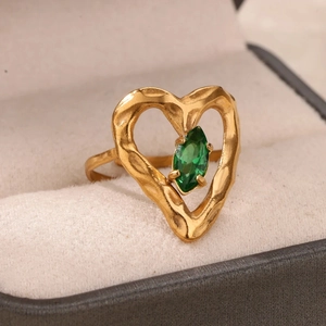 Dettaglio di un anello a cuore dorato con zircone verde marquise in una confezione