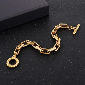 Détail du bracelet gourmette en acier doré avec fermoir à bascule OT sur fond noir texturé