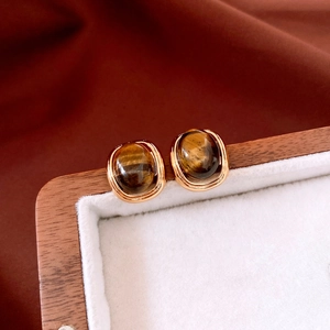 Macro view of 18k gold plated tiger eye stone stud earring on vintage jewelry box