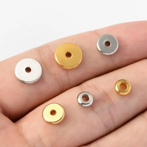 Flat stainless steel abacus beads in gold and silver on a finger showing various sizes
