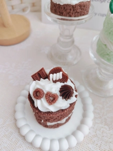 Close-up of chocolate layered cake scented candle with creamy frosting and cookie topping