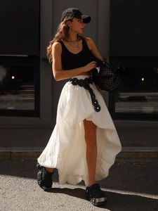 Détail d'une jupe blanche en coton avec ourlet asymétrique et ceinture noire ronde