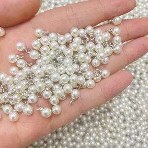 Close-up van glanzende witte imitatieparel hangers met zilveren metalen lussen voor sieraden