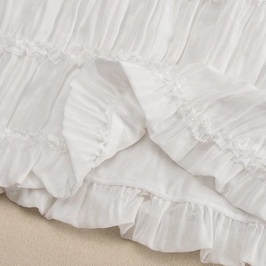 Macro detail of white pleated fabric with delicate lace edges and breathable texture