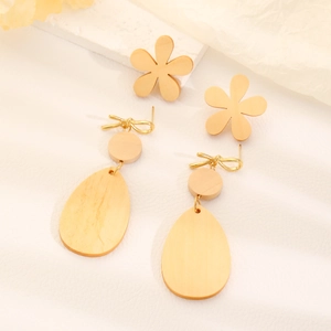 Detail of wooden flower earrings with gold bow and large teardrop drop on stone base
