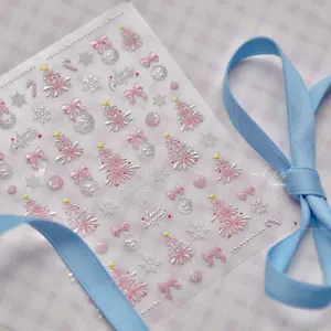 Macro shot of 3D embossed pink Christmas tree and snowflake nail stickers on grid fabric