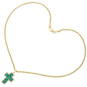 Macro shot of gold cross pendant with green gemstone in a heart-shaped chain layout