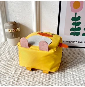 Detail view of the cute yellow duck toddler backpack with soft felt features on white surface