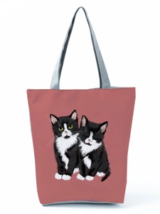 Detail shot of a dusty pink tote bag featuring two cute cartoon cats with grey handles