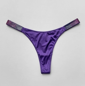 Close-up of purple satin thong with sparkling rhinestone side straps on a gray background