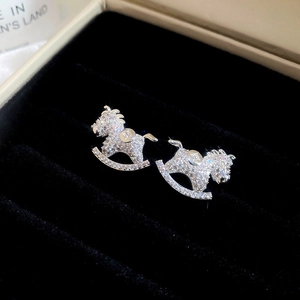Detailed view of silver horse earrings with sparkling zircons in a black velvet box