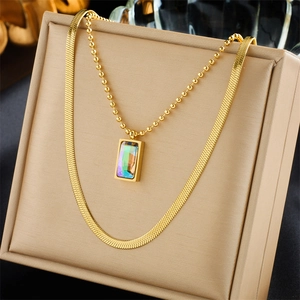 Layered gold snake and bead chain necklace with iridescent rainbow crystal pendant