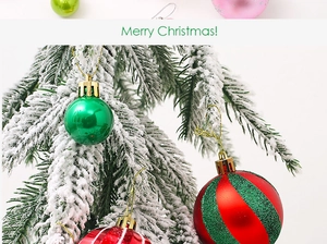 Close-up of decorative Christmas balls hanging on snow-covered pine branches with Merry Christmas text