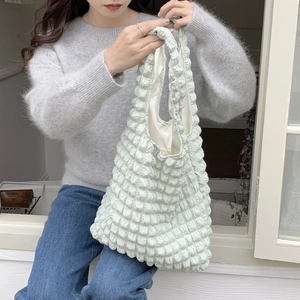 Detail of mint green puffy cloud tote bag with bubble texture fabric on a casual model