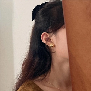 Detail view of a vintage gold-plated round stud earring worn by a model