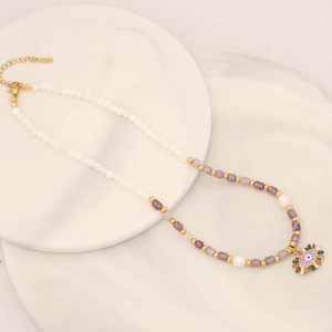 Dettaglio del ciondolo occhio malvagio con gemme colorate e collana di perle miste