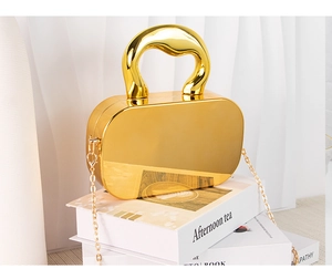 Detail view of the gold acrylic mirror box clutch featuring a metallic chain shoulder strap