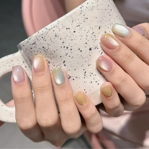 Close-up of cat-eye press-on nails in soft pastel shades holding a ceramic cup