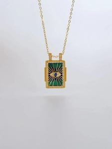 Macro detail of gold tarot card pendant with emerald enamel and evil eye crystal stones