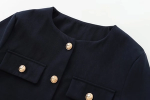 Close-up of golden buttons and textured fabric on a dark navy short tweed jacket