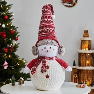 Poupée bonhomme de neige de Noël avec bonnet et écharpe rouges dans un décor de fête chaleureux