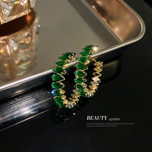 Luxurious green zircon C-shape hoop earrings with gold plating on black reflective tray
