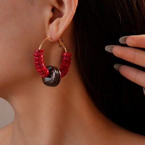 Detail view of retro ethnic coconut shell beaded hoop earring worn by a model