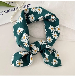 Close-up of dark green silk scarf with white daisy print and elegant pearl accessories