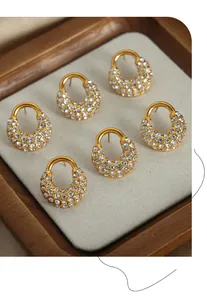 Gros plan de trois paires de boucles d'oreilles en or en U avec zircons sur velours