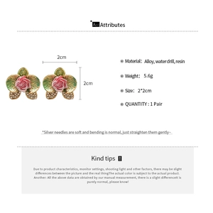 Detail view of floral earrings with pink roses, green leaves and silver needles