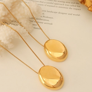 Minimalist gold plated oval pendant necklace with a fine box chain on a vintage book