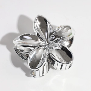 Macro detail of silver metal lily hair claw with polished mirror finish and teeth
