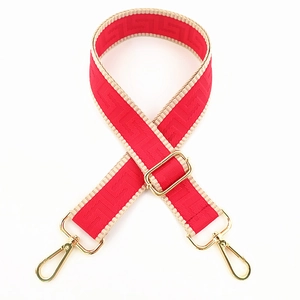 Close-up of red Greek Key nylon bag strap with gold metal hooks and adjustable buckle