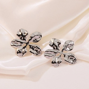 Elegant silver flower stud earrings with hammered metal texture on white satin background