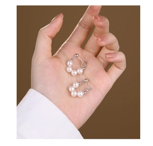 Detail view of s925 silver beaded hoop earrings with white pearls held in a hand