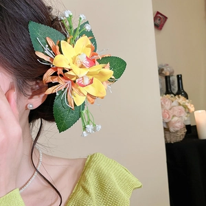 Detail of elegant yellow fabric flower hair clip worn on a model in a warm setting