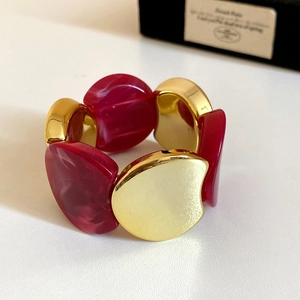 Macro detail of chunky acrylic resin bracelet with wavy gold metal segments