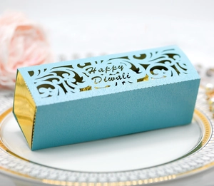 Blaue lasergeschnittene Diwali-Geschenkbox mit Goldakzenten auf weißem Teller
