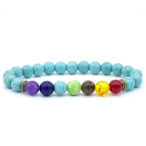 Macro shot of colorful seven chakra beads and blue turquoise stones on elastic bracelet