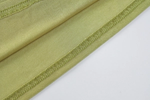 Gros plan du tissu en maille verte montrant les coutures et détails de finition