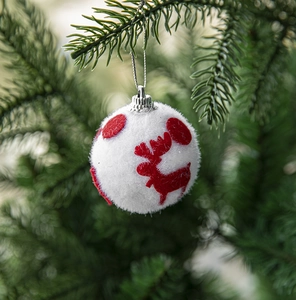 Close-up of white plush Christmas ball with red reindeer hanging on a pine tree branch