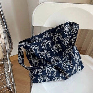 Detail of navy canvas tote bag featuring white sheep patterns on a modern chair