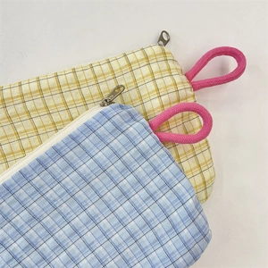 Close-up of checkered fabric coin pouches with pink woven wrist straps and metal zippers