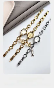 Detail of oval quartz watch bands with small bee and fish charms in three metallic tones