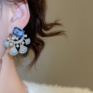 Detailed close-up of a fan-shaped earring with blue crystals and sparkling rhinestones