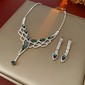 Close-up of sparkling rhinestone tassel necklace and earrings set with green gemstones